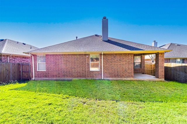 back of house with a fenced backyard, a yard, and roof with shingles