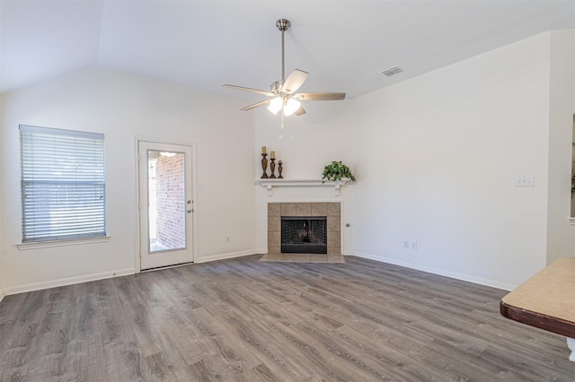 unfurnished living room featuring visible vents, a tile fireplace, ceiling fan, wood finished floors, and vaulted ceiling