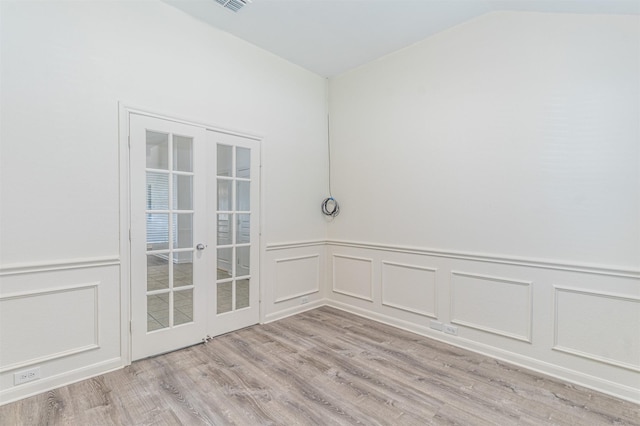 spare room with french doors, visible vents, a decorative wall, light wood-style flooring, and vaulted ceiling