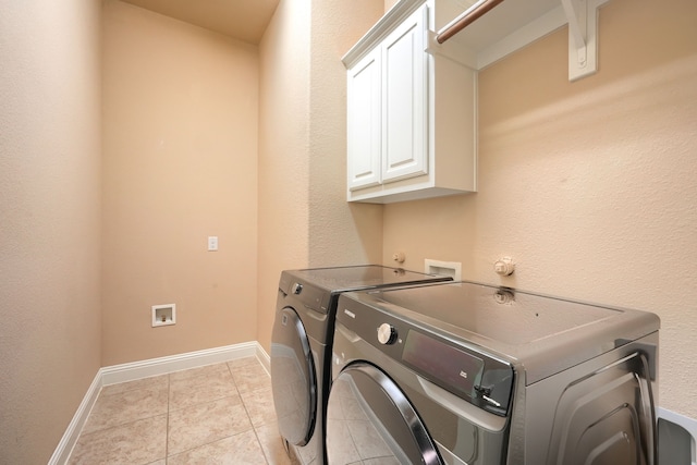 laundry area with light tile patterned floors, baseboards, cabinet space, and washer and dryer