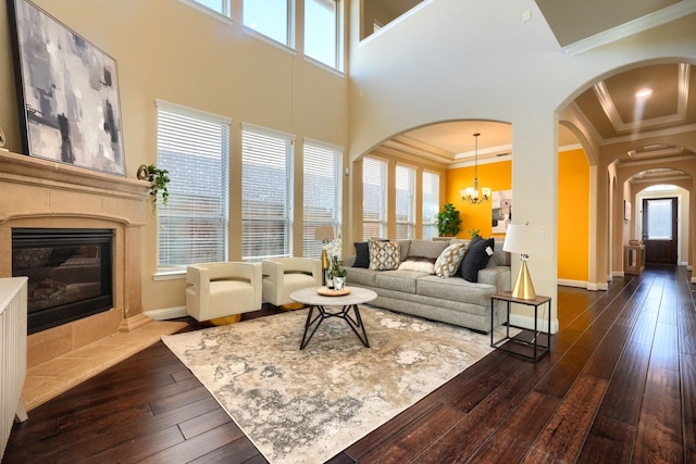 living area with dark wood finished floors, crown molding, a premium fireplace, a healthy amount of sunlight, and a chandelier