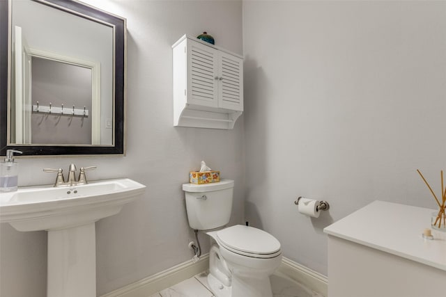 bathroom with marble finish floor, a sink, toilet, and baseboards