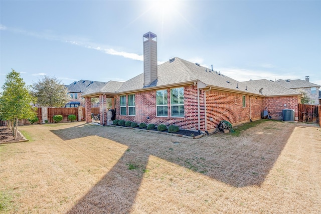 back of property with brick siding, a shingled roof, a lawn, cooling unit, and a fenced backyard