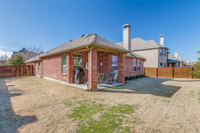 back of property featuring a yard, brick siding, a patio, and a fenced backyard