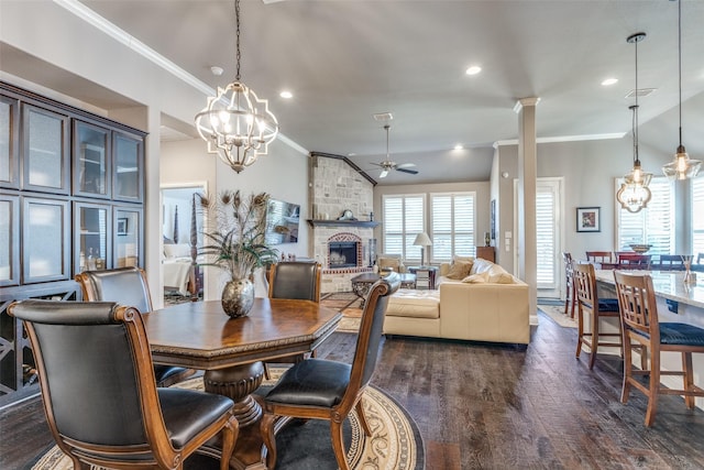 dining room with a large fireplace, decorative columns, a ceiling fan, ornamental molding, and dark wood-style flooring