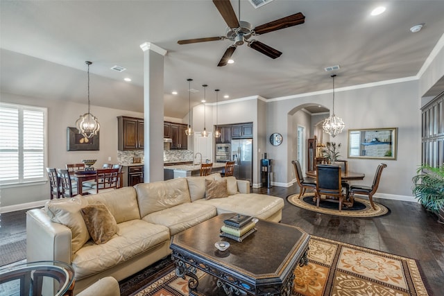 living area with dark wood-style floors, arched walkways, visible vents, and crown molding