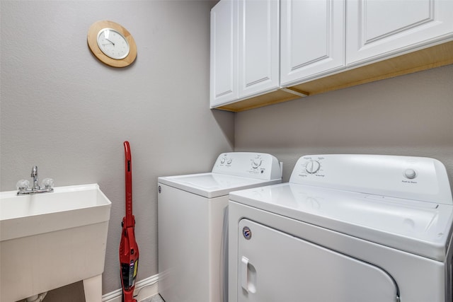 washroom with cabinet space, washing machine and dryer, a sink, and a textured wall