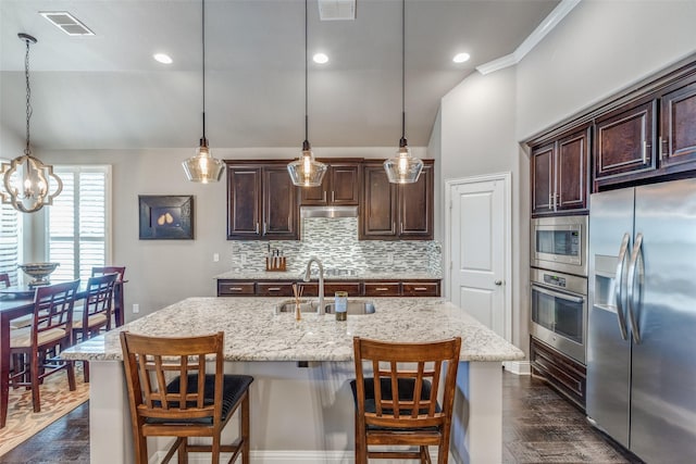 kitchen with dark brown cabinetry, stainless steel appliances, a sink, visible vents, and decorative backsplash