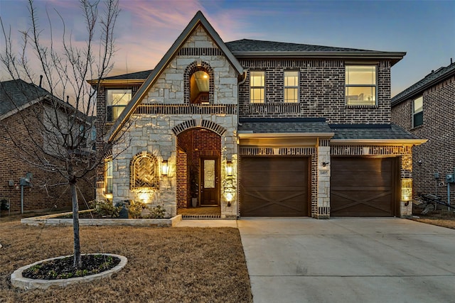 view of front of house featuring brick siding, concrete driveway, an attached garage, a balcony, and stone siding