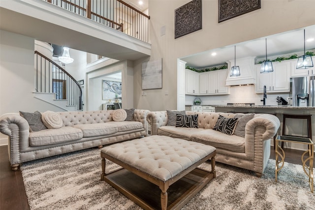 living room with stairs, a towering ceiling, and wood finished floors