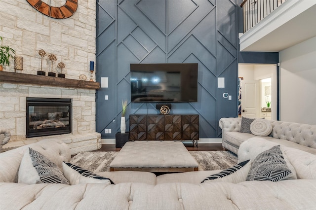 living area with a fireplace, a towering ceiling, baseboards, and wood finished floors