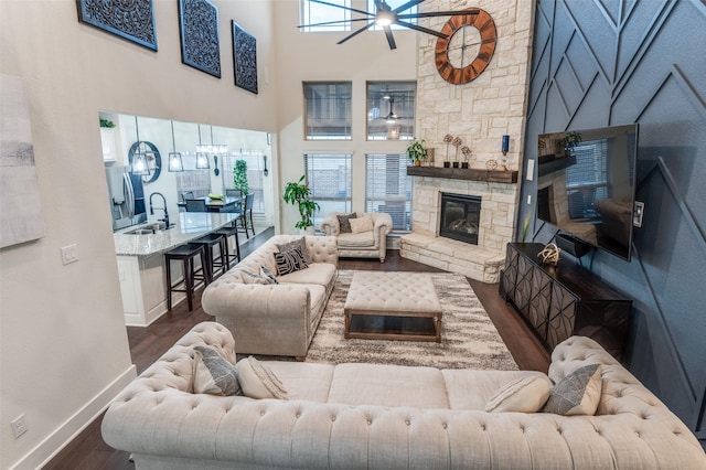 living room featuring dark wood-type flooring, a fireplace, a high ceiling, and baseboards