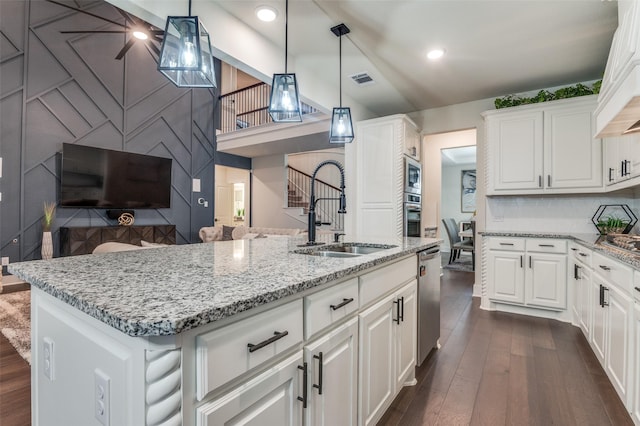 kitchen featuring stainless steel appliances, dark wood-type flooring, a sink, white cabinetry, and light stone countertops