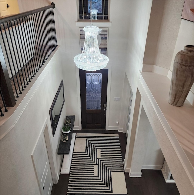 foyer featuring baseboards, stairway, a towering ceiling, and an inviting chandelier