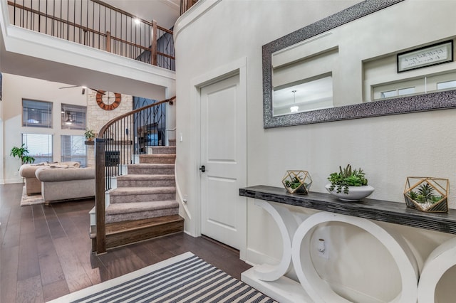 stairway featuring baseboards, a high ceiling, and hardwood / wood-style flooring