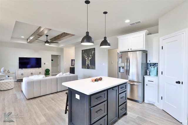 kitchen with light wood-style floors, stainless steel fridge, a kitchen island, and white cabinets