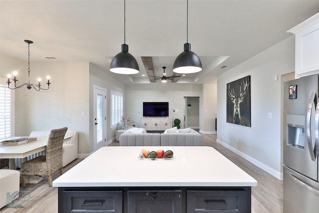 kitchen with light countertops, light wood-style floors, a wealth of natural light, and stainless steel fridge with ice dispenser