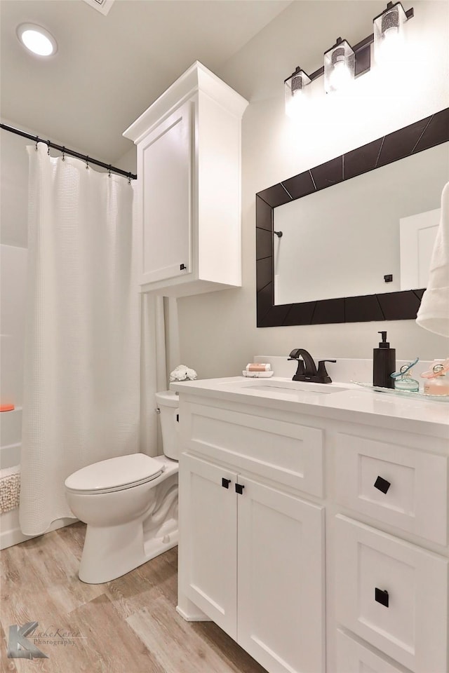 bathroom with toilet, wood finished floors, and vanity