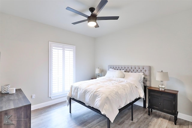 bedroom with multiple windows, wood finished floors, a ceiling fan, and baseboards