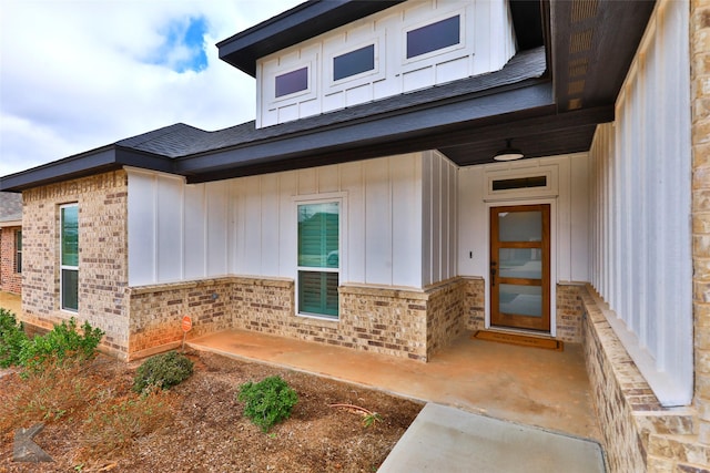 doorway to property with board and batten siding and brick siding