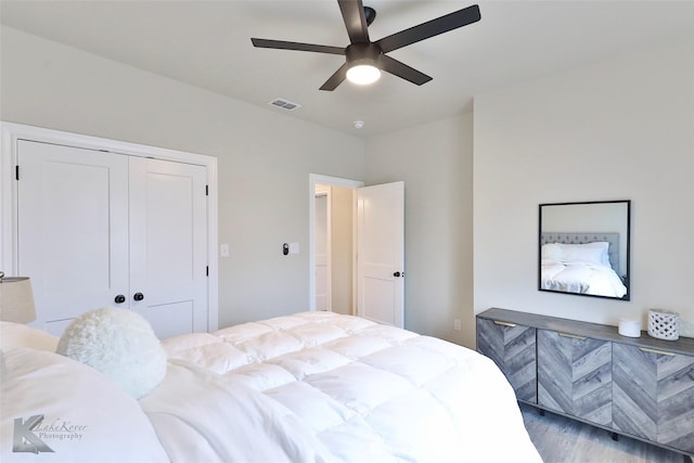 bedroom featuring ceiling fan, visible vents, a closet, and wood finished floors