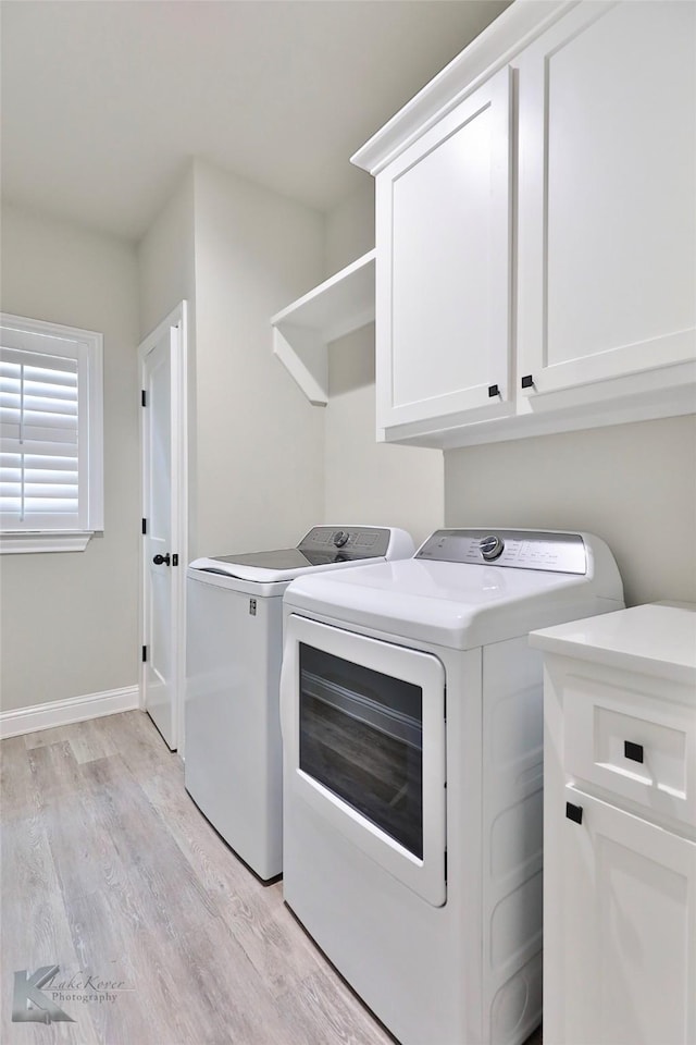 laundry room with baseboards, washing machine and clothes dryer, cabinet space, and light wood-style floors