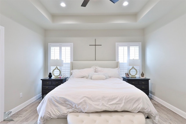 bedroom with baseboards, multiple windows, and a tray ceiling