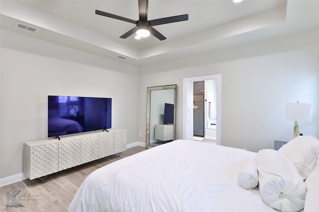 bedroom featuring a tray ceiling, wood finished floors, and visible vents