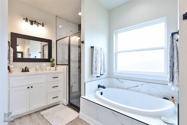 full bathroom featuring wood finished floors, a stall shower, vanity, and a bath