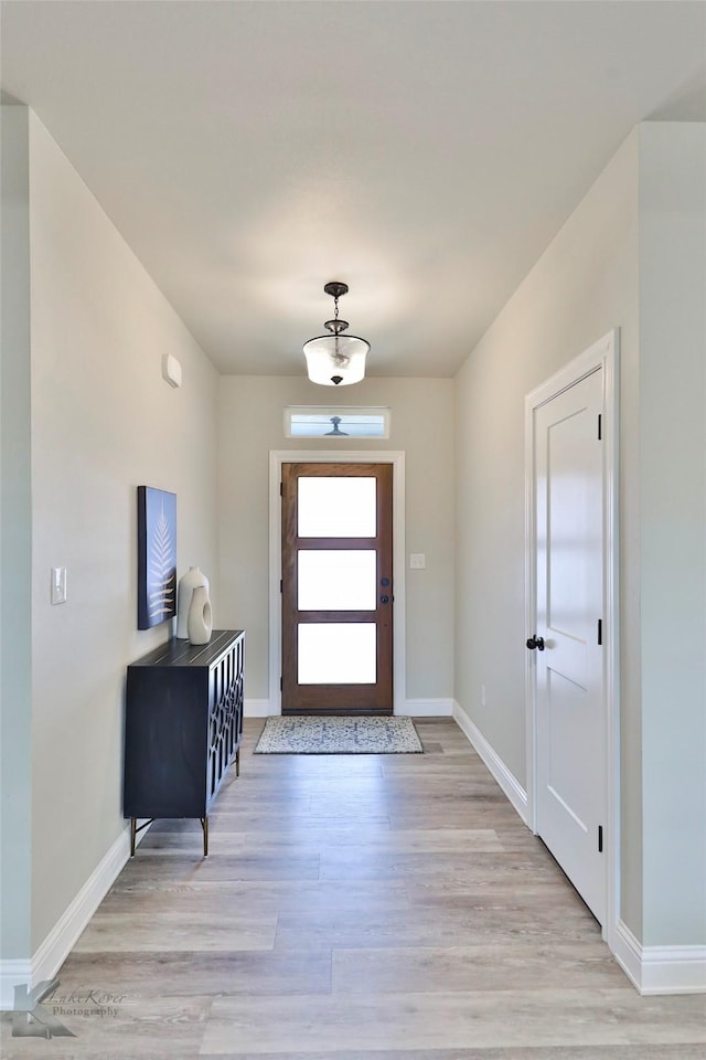 foyer entrance with light wood-style flooring and baseboards