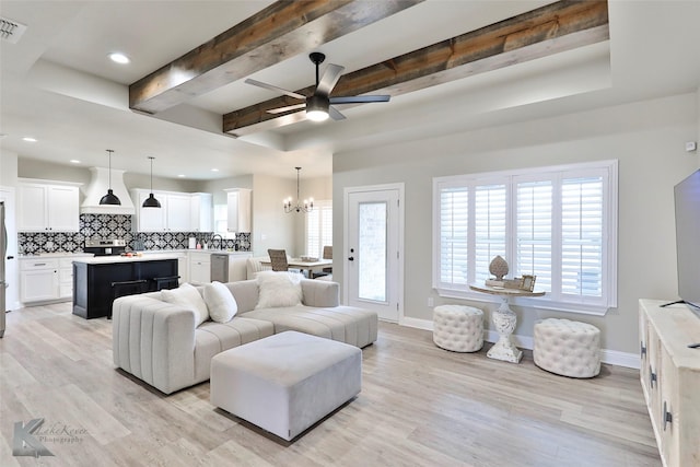 living area with light wood-type flooring, beam ceiling, and baseboards