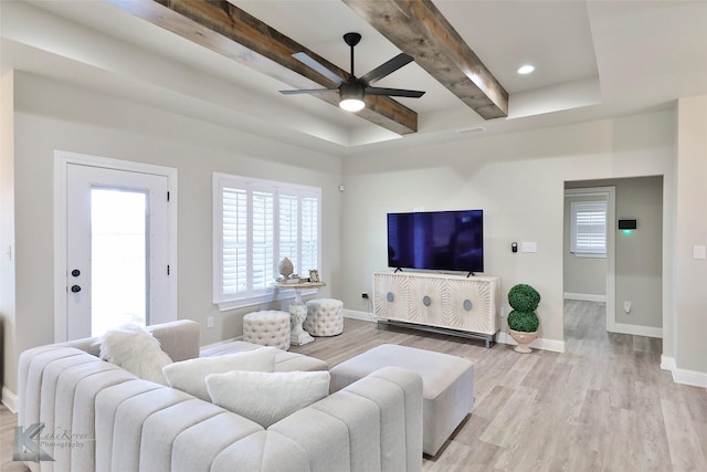 living area with light wood finished floors, visible vents, baseboards, and beamed ceiling