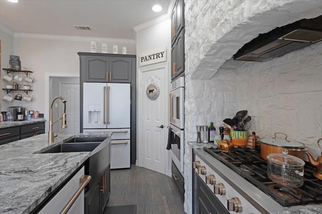 kitchen with light stone counters, visible vents, gas stovetop, ornamental molding, and white fridge with ice dispenser