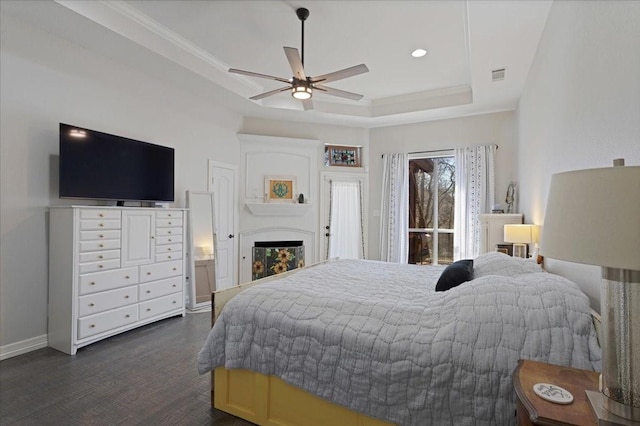 bedroom with a tray ceiling, visible vents, baseboards, and crown molding