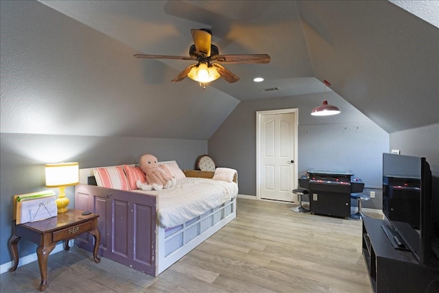 bedroom with baseboards, visible vents, light wood finished floors, lofted ceiling, and ceiling fan