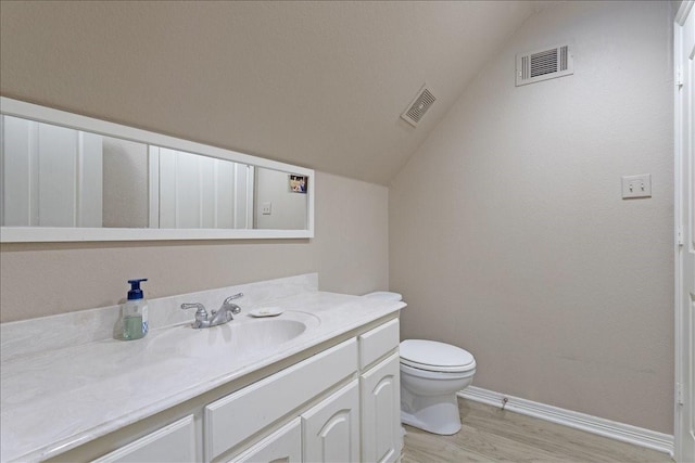 bathroom with vanity, vaulted ceiling, wood finished floors, and visible vents