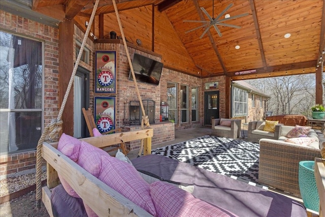 exterior space with high vaulted ceiling, wooden ceiling, brick wall, ceiling fan, and an outdoor brick fireplace