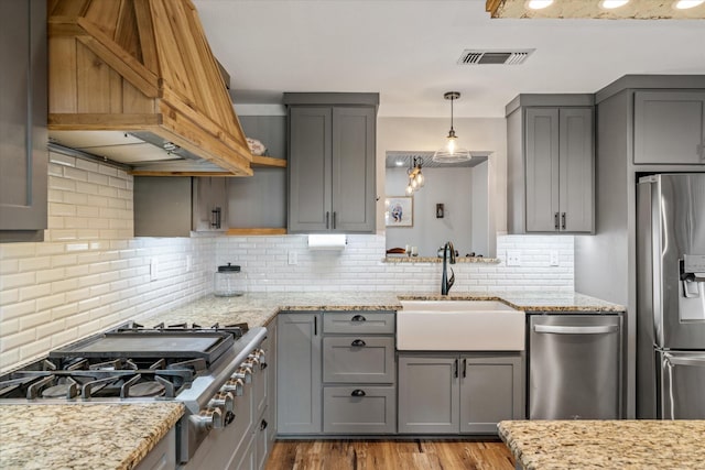 kitchen with appliances with stainless steel finishes, a sink, and gray cabinetry