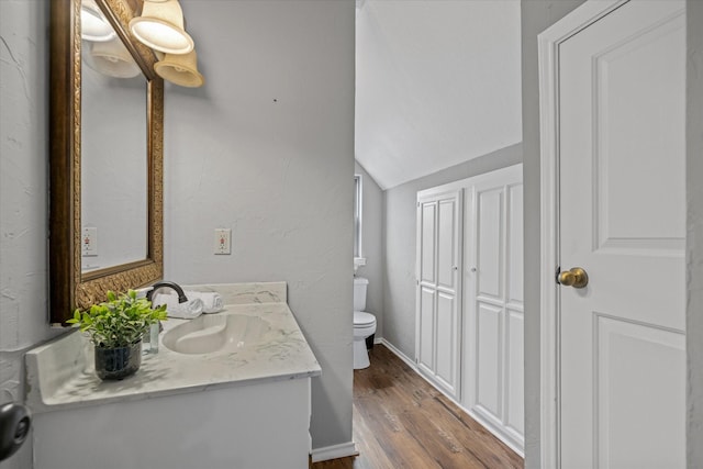 bathroom with baseboards, a textured wall, toilet, wood finished floors, and vanity