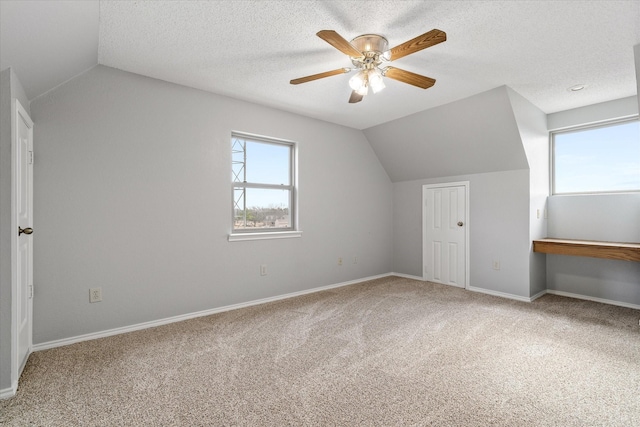 bonus room with a textured ceiling, ceiling fan, carpet floors, baseboards, and vaulted ceiling