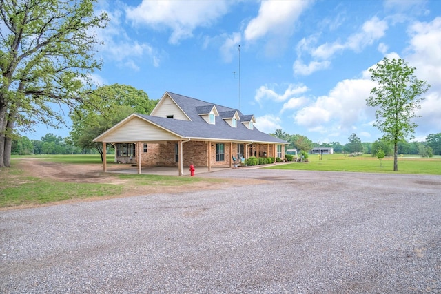 view of front of home featuring an attached carport, brick siding, a shingled roof, driveway, and a front yard