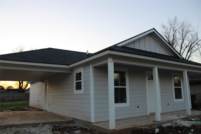 view of front of house with a shingled roof, board and batten siding, and fence