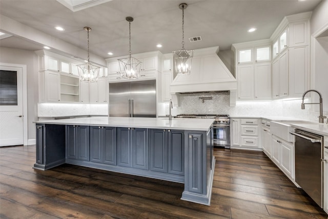 kitchen featuring a center island with sink, visible vents, custom range hood, high quality appliances, and a sink