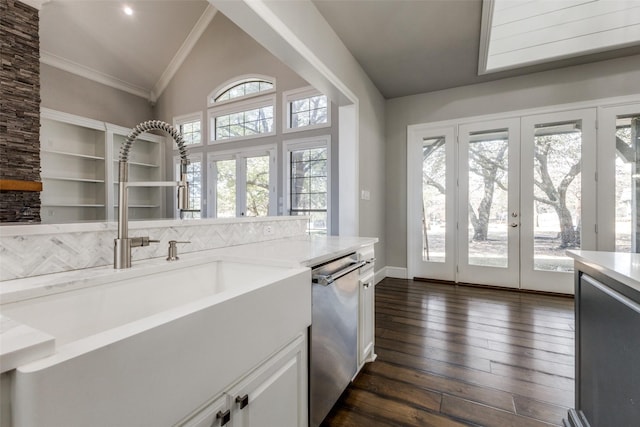 kitchen with lofted ceiling, dark wood-style floors, french doors, stainless steel dishwasher, and a sink