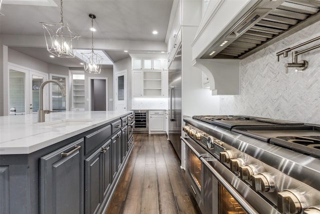 kitchen with white cabinets, high end appliances, wine cooler, custom range hood, and a sink