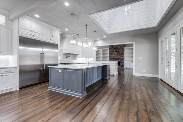 kitchen with white cabinets, custom range hood, stainless steel appliances, and light countertops