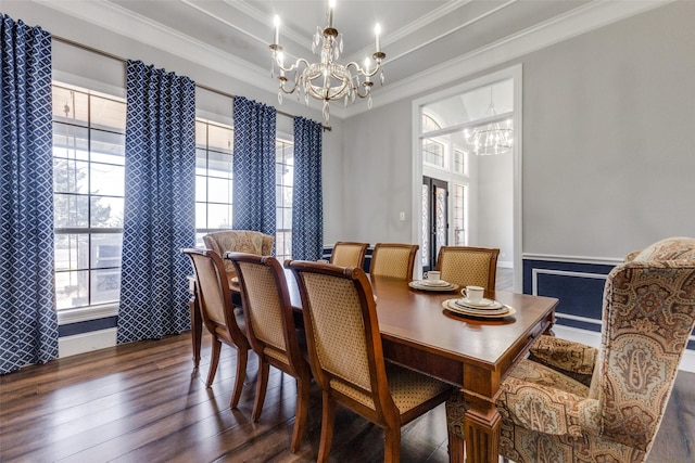 dining area with a tray ceiling, ornamental molding, wainscoting, a chandelier, and hardwood / wood-style floors