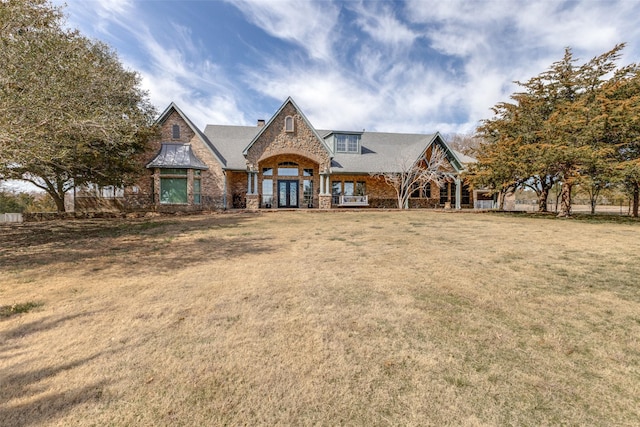 view of front of house with stone siding, french doors, and a front yard