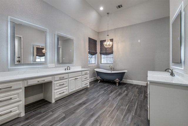 bathroom with visible vents, baseboards, a soaking tub, wood finished floors, and vanity