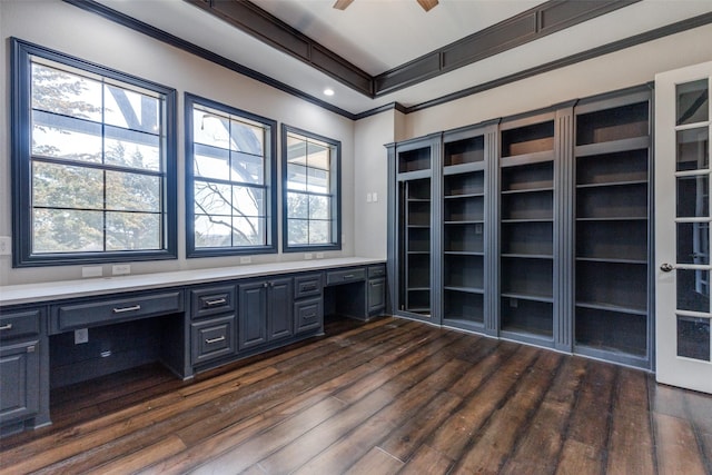 unfurnished office with a ceiling fan, dark wood-style flooring, crown molding, and built in desk